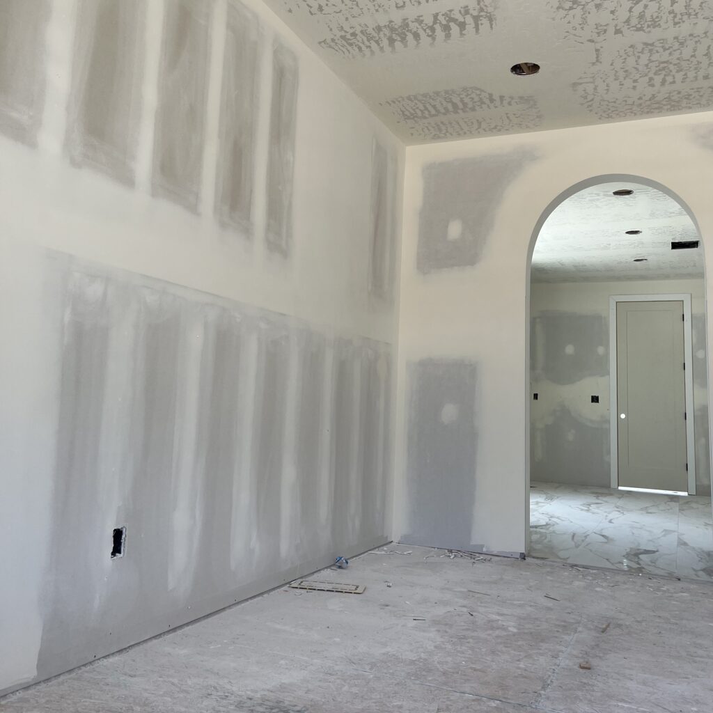Shows room with newly installed drywall ready for paint